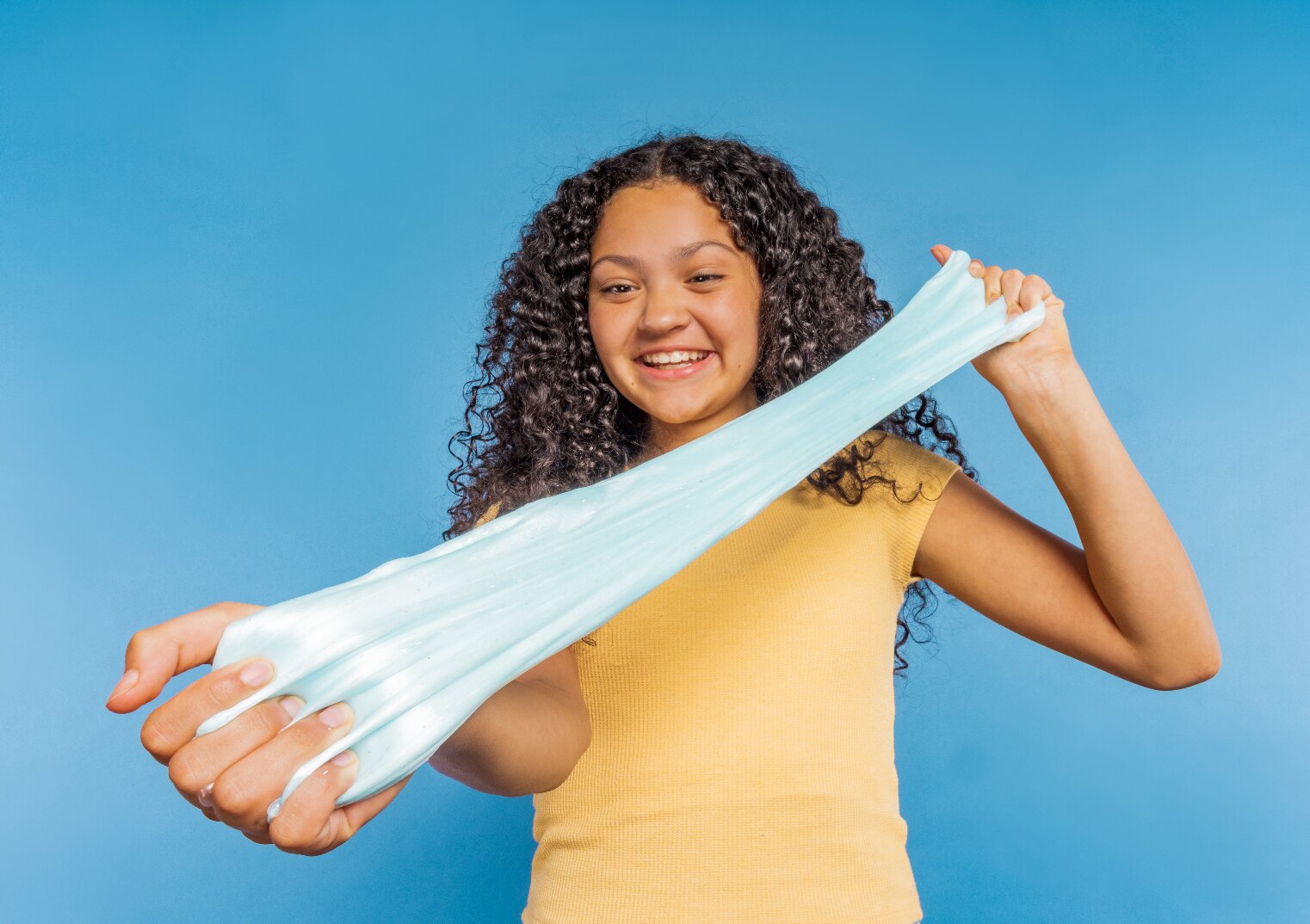 Girl stretching blue Elmer's slime on a blue background