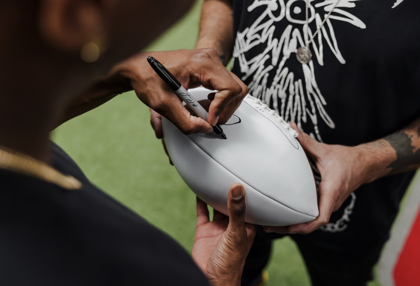 Close-up of a Sharpie signing a football on field turf