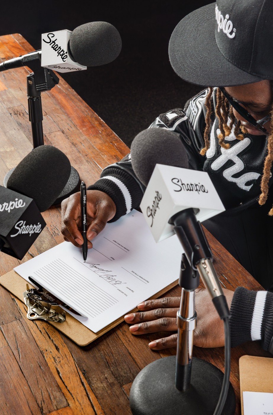 Overhead shot of an athlete signing autographs at the Sharpie press desk